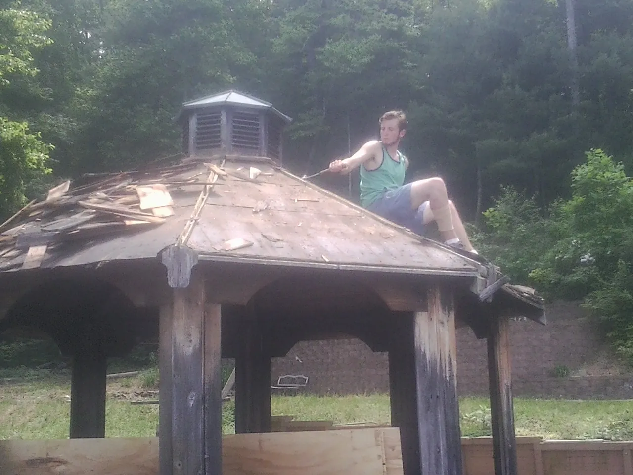 Tearing the old roof off a wooden gazebo before new shakes in Evanston