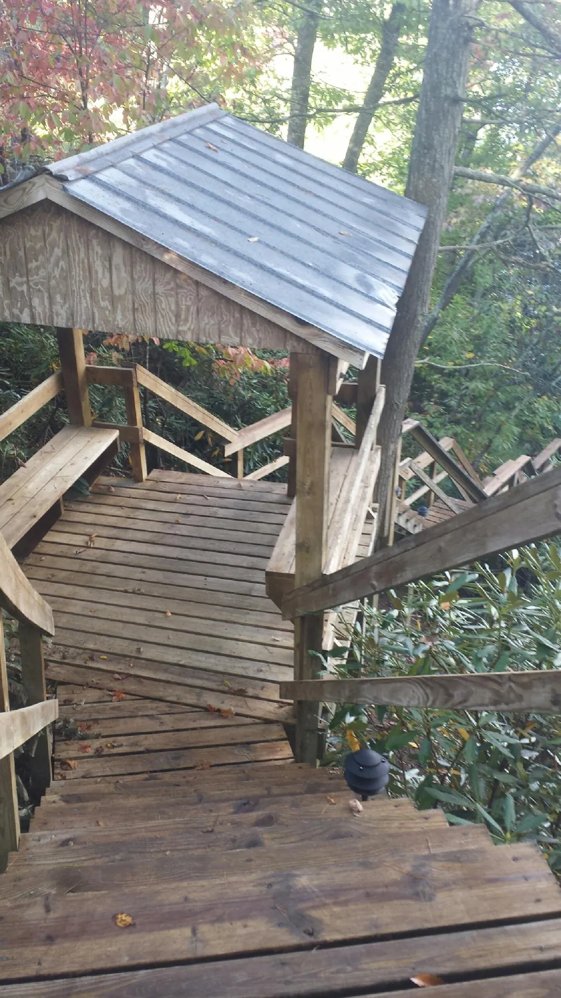 Metal roofed shelter over wooden steps on a wooded walkway — Skylight Repair & Installation work by our crew in Evanston